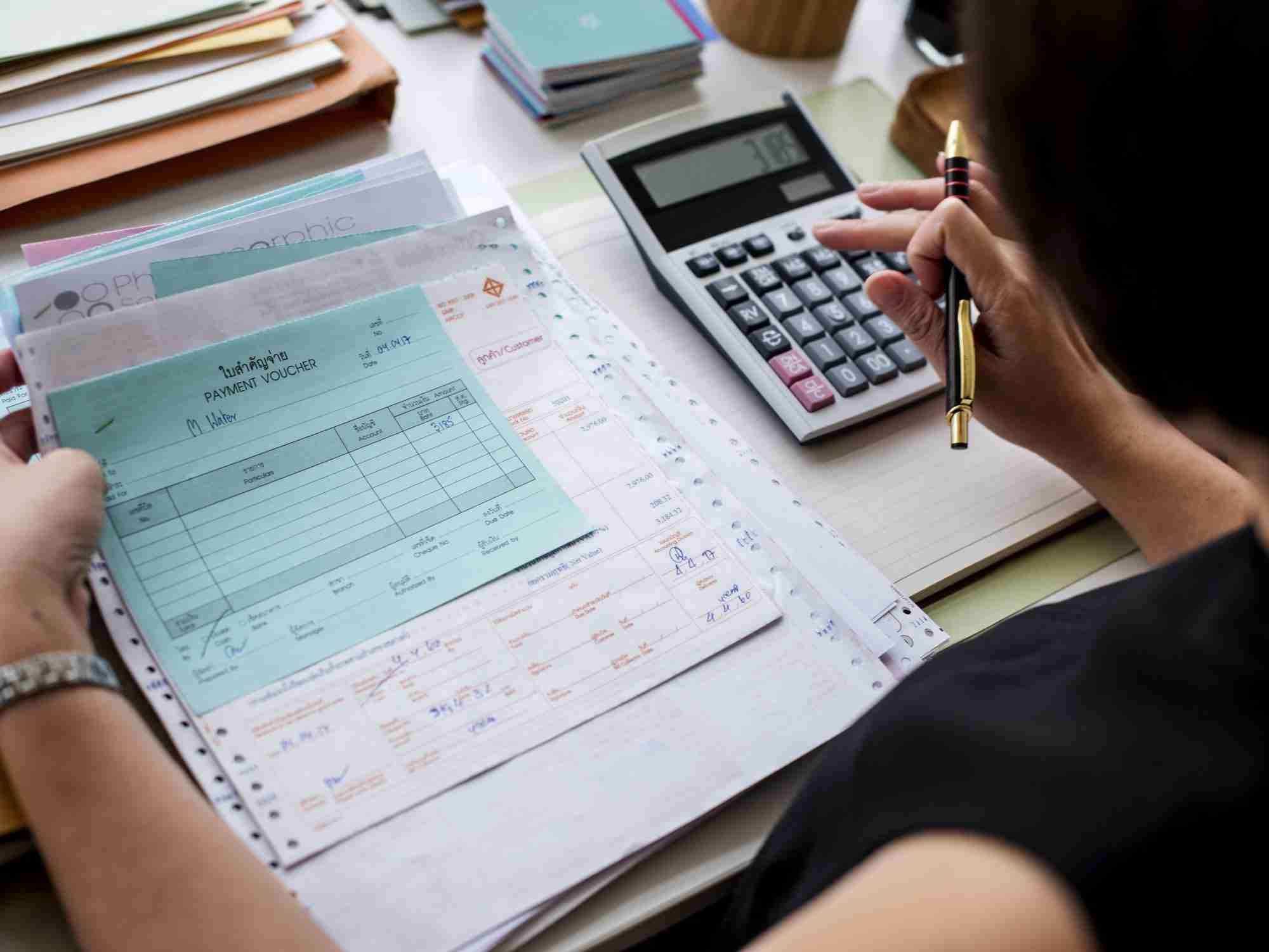 asian woman working through paperwork edited scaled