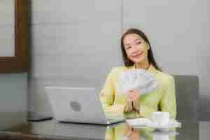 portrait beautiful young asian woman use computer laptop with smart mobile phone working table interior room